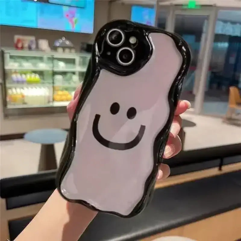 a person holding a phone case with a smiley face on it