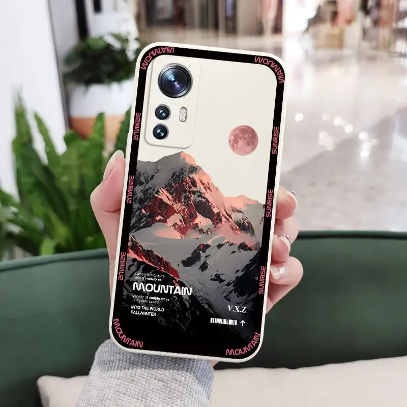 A person holding a phone with a mountain scene on it