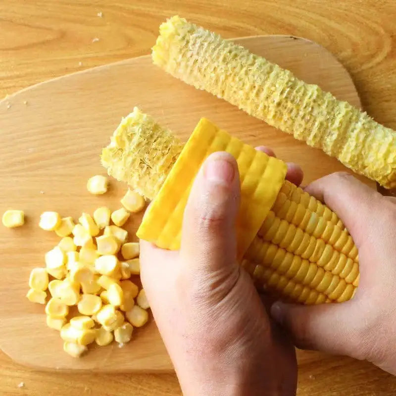 a person cutting a piece of corn on a wooden cutting board