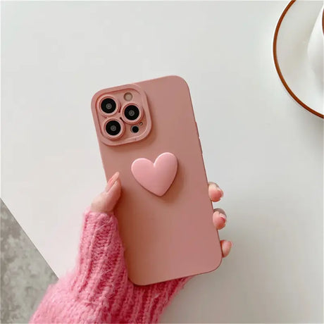 A person holding a pink heart phone case