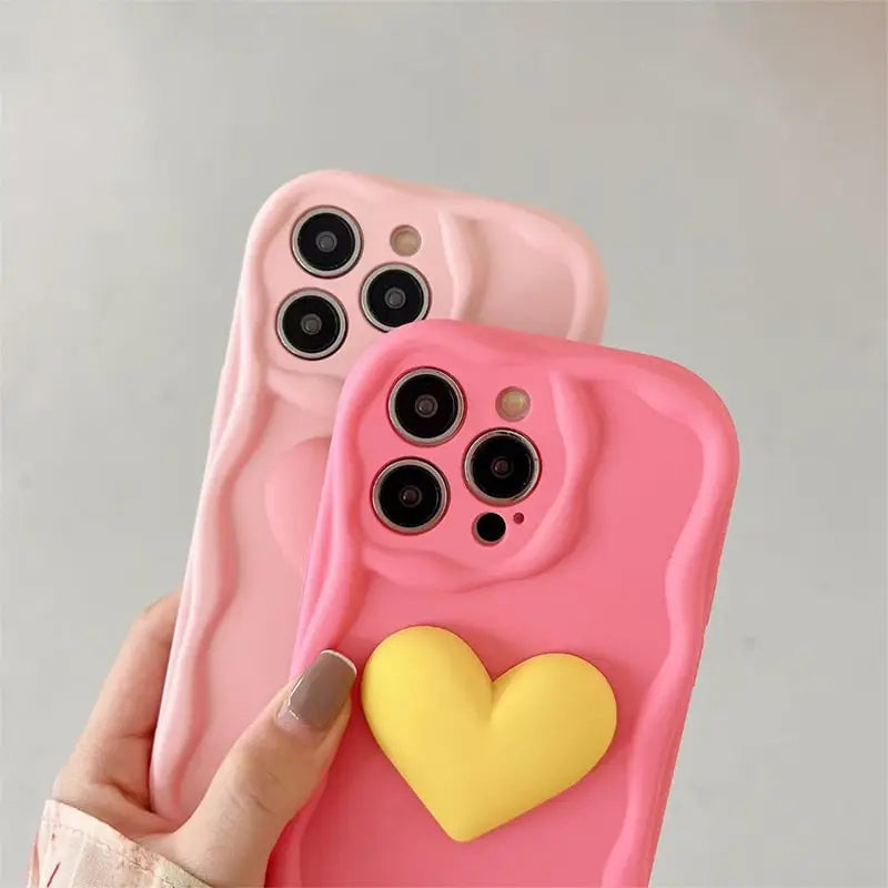 A person holding a pink phone case with a heart