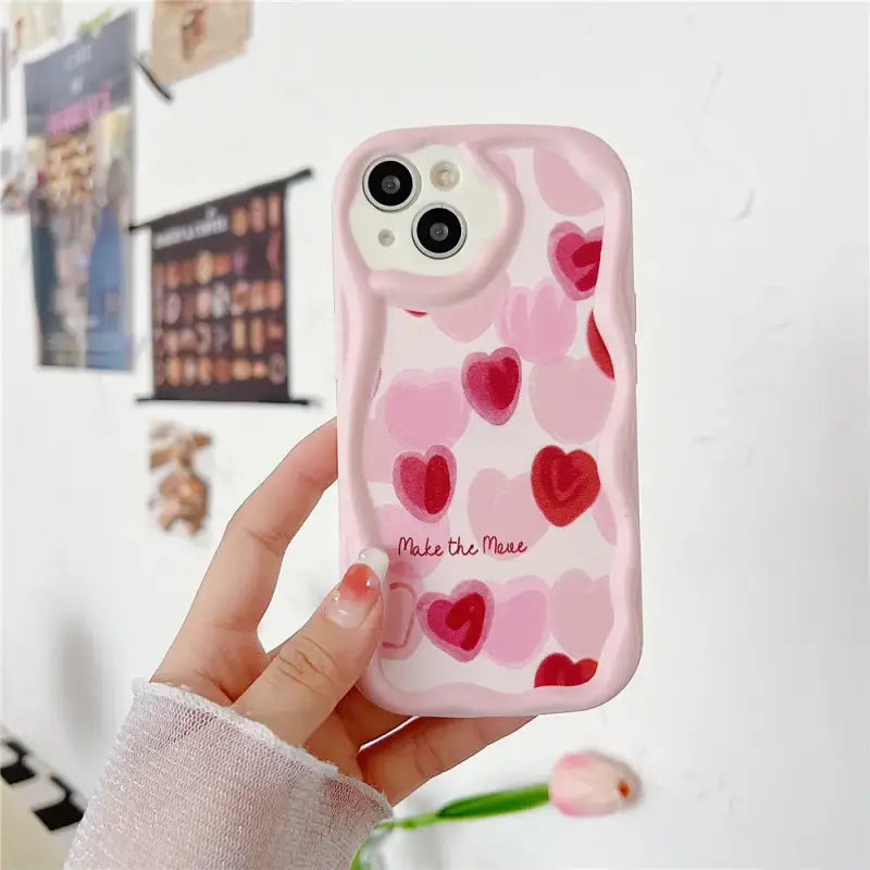 a person holding a pink phone case with hearts on it