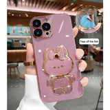 a person holding a pink phone case with a gold hello kitty