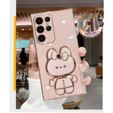 A person holding a pink phone case with a hello bear