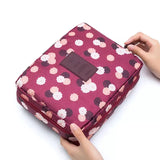 a person holding a pink and white flower print cosmetic bag