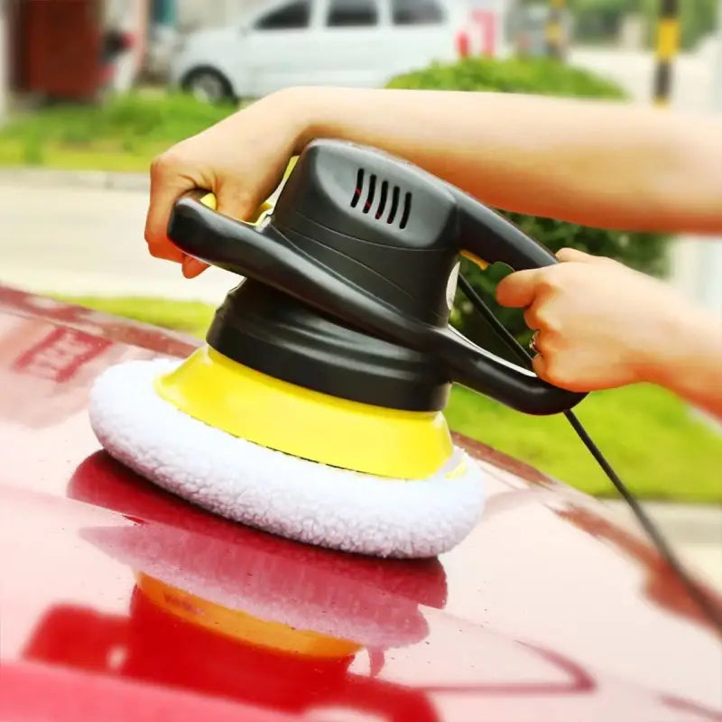 a person using a spray gun to clean the car