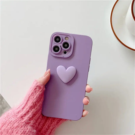 A person holding a purple phone case with a heart on it