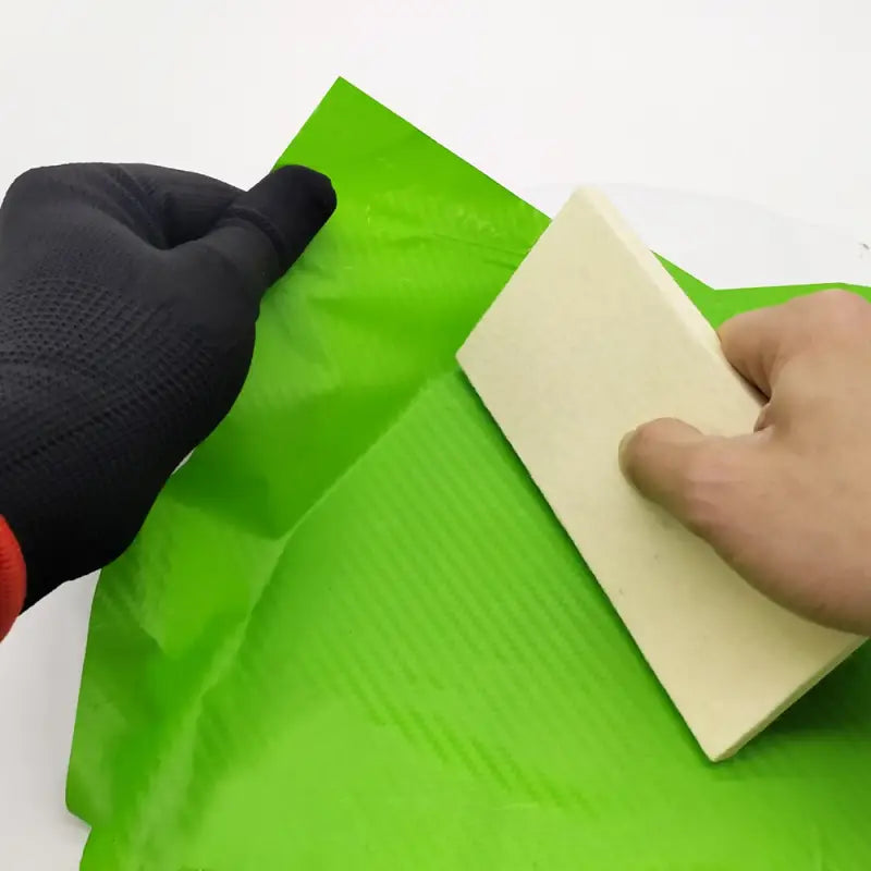 a person using a sponge to clean a green bag