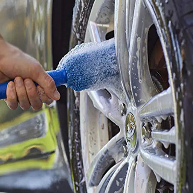 a person using a sponge to clean a car tire