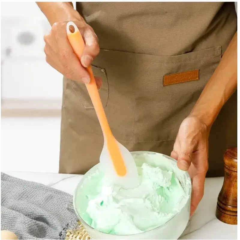 a person is holding a spoon with green cream