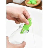 a person is squeezing a green substance into a glass bottle