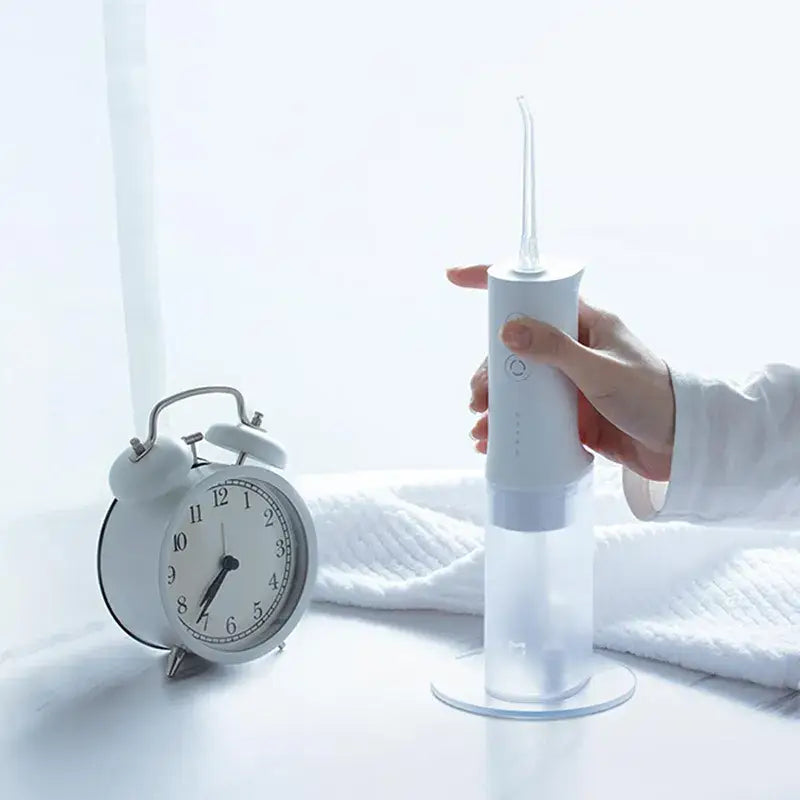 A person holding a toothbrush next to a clock