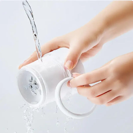 A person pouring water from a white cup