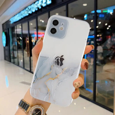 A person holding a white phone case with a marble pattern