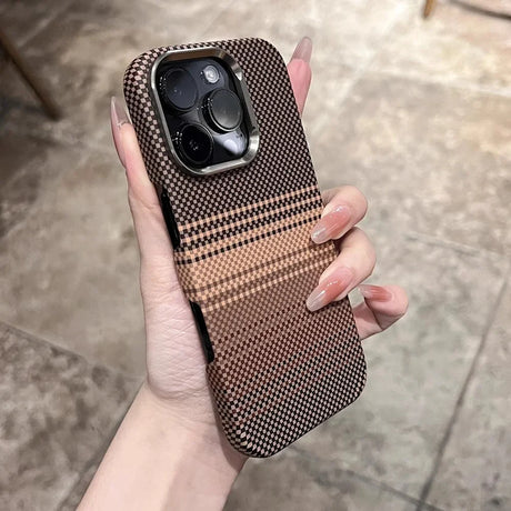 A person’s hand holding a phone case with a black and brown checkered pattern and a metallic camera bezel.
