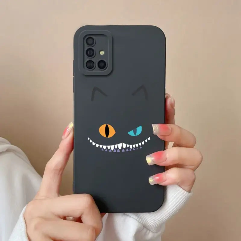 someone holding a phone with a black case with a cat face on it