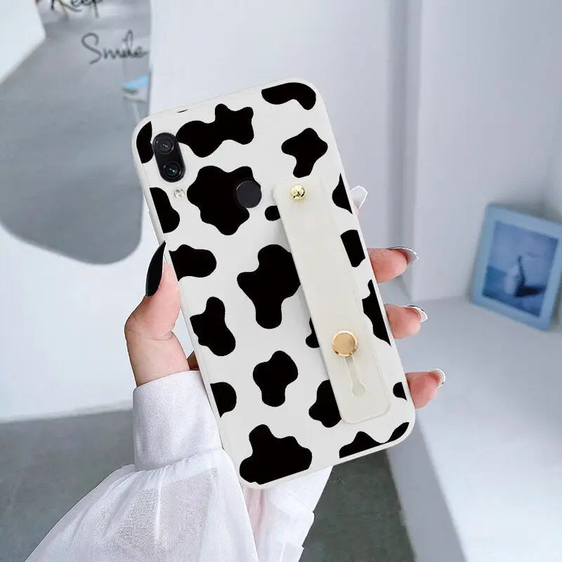 a woman holding a phone case with a cow print