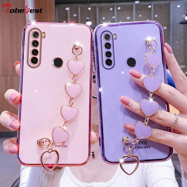two women holding up their phone cases with heart charms