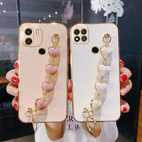 a woman holding two iphone cases with heart charms