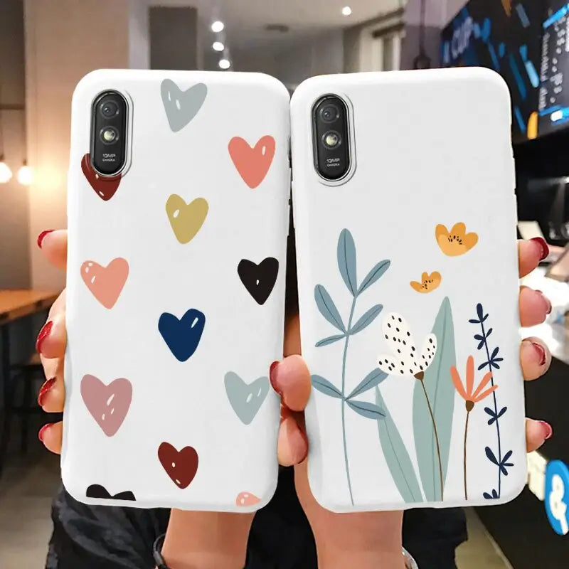 two women holding up their phone cases with hearts and flowers