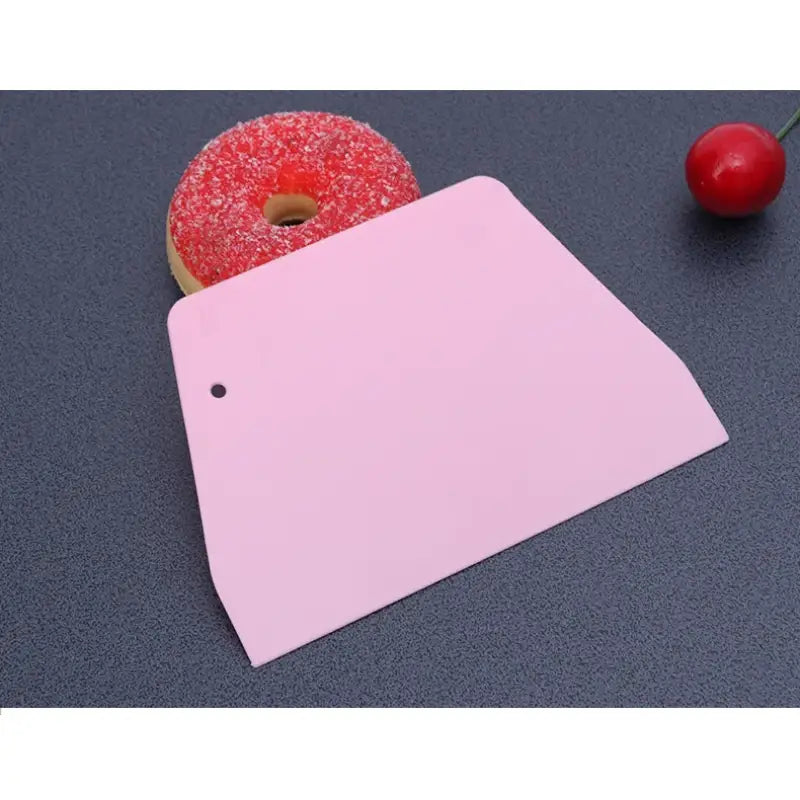 a pink cutting board with a donut and a cherry