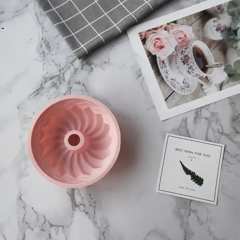 there is a pink cake pan and a card on a marble table