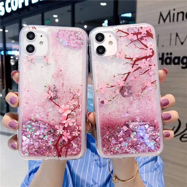 a woman holding two iphone cases with pink glitter and pink flowers