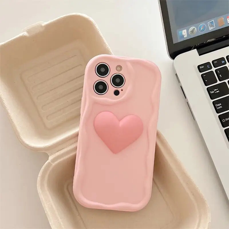 a pink heart phone case sitting on top of a laptop