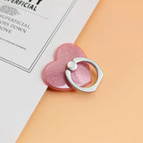 a pink heart shaped ring on a white sheet