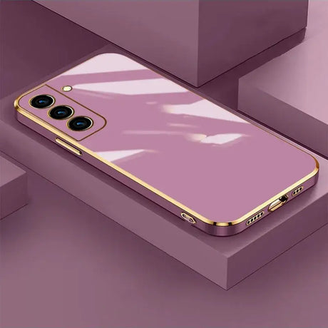 A pink iphone case with gold trim and a white background