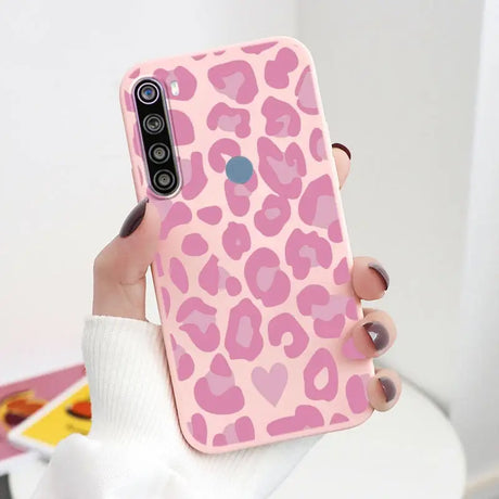 a woman holding a pink leopard print phone case