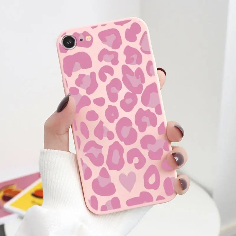 a woman holding a pink leopard print phone case