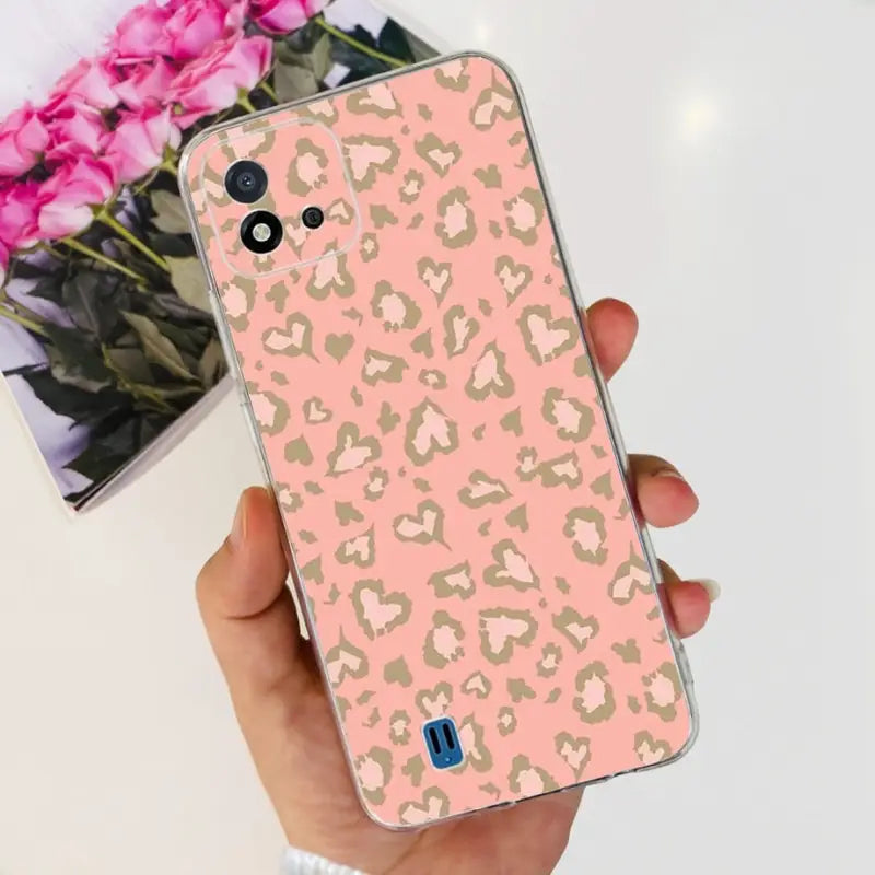 a woman holding a pink and gold leopard print iphone case