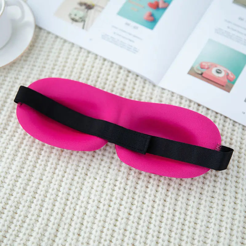 a pink eye mask with black band on top of a white table