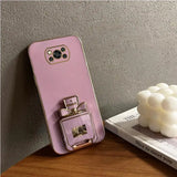 A pink phone case with a perfume bottle on top