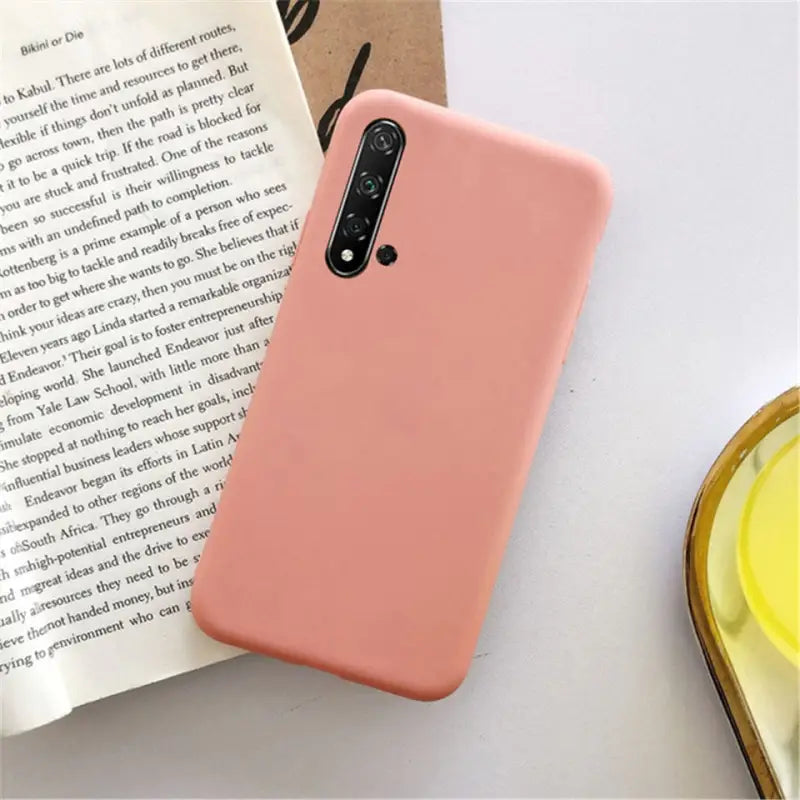 a pink phone case sitting on top of a book