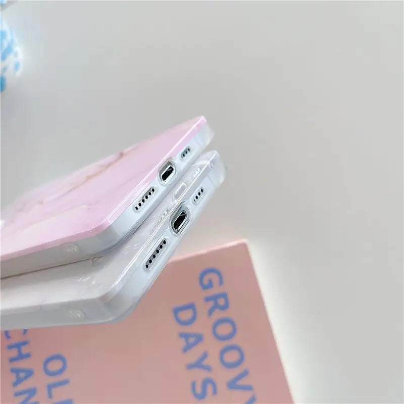 a pink phone case sitting on top of a pink book
