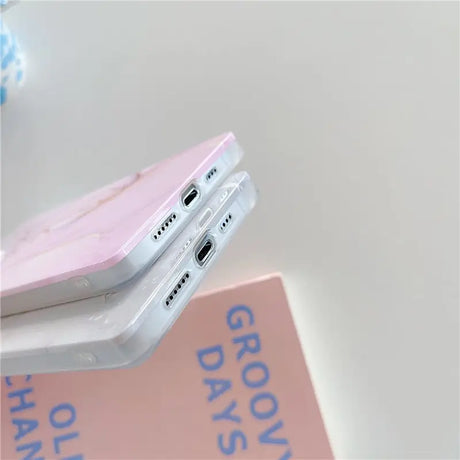 a pink phone case sitting on top of a pink book