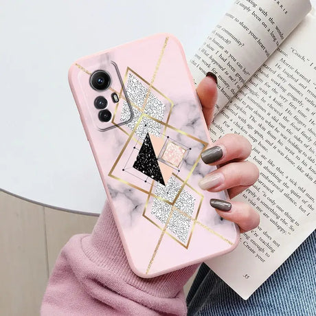 Someone holding a pink phone case with a triangle and glitter on it