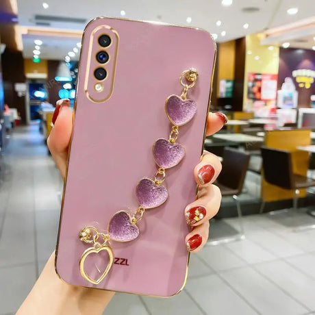 Pink smartphone case adorned with a decorative chain of purple heart charms.