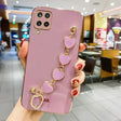 Pink smartphone case with a decorative gold heart charm accessory attached.