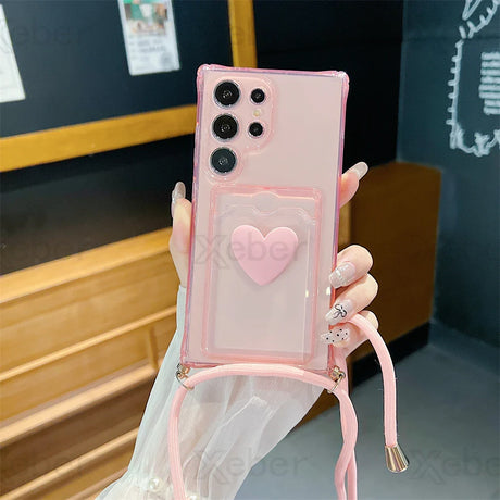 Pink smartphone case with a heart-shaped design and shoulder strap.
