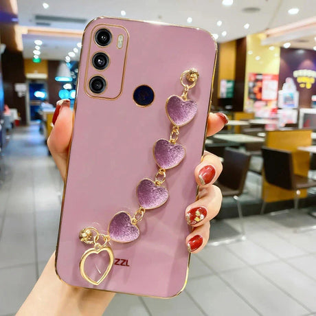 Pink smartphone with a decorative heart-shaped charm attached.