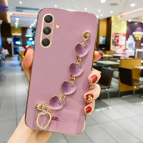 Pink smartphone with a decorative heart-shaped charm attached.