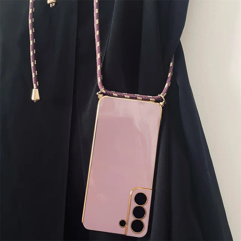 Pink smartphone with a gold-trimmed case and a purple cord strap.