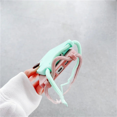 A pink smartphone in a mint green and pink strapped phone case.