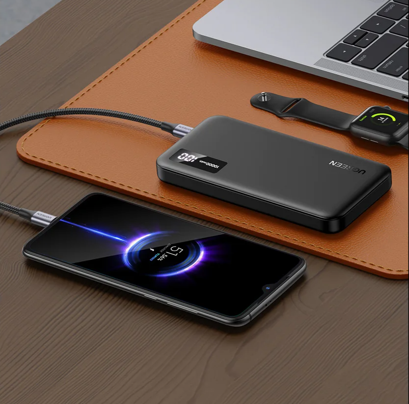 Portable battery pack charging a smartphone with a glowing display.