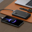 Portable battery pack charging a smartphone with a glowing circular display.