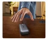 Portable external hard drive with a hand hovering above it.