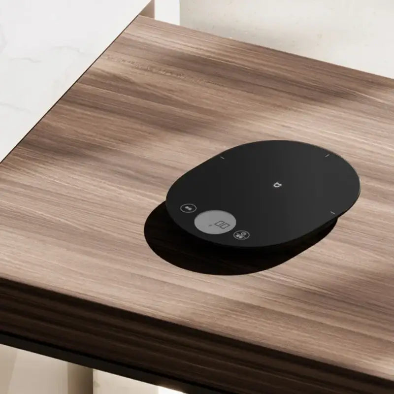 a black google home hub on a wooden table